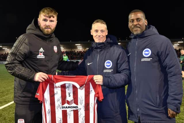 Paddy McCourt presenting a signed Derry City shirt to Brighton & Hove Albion coaches Patrick Rocks and Stu Lawrence at the Brandywell on Friday night. DER1419-108KM