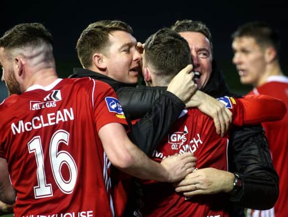 Jamie McDonagh celebrates with teammates and Derry City coaches, Kevin Deery and Marty McCann after netting a late goal against Cork City.