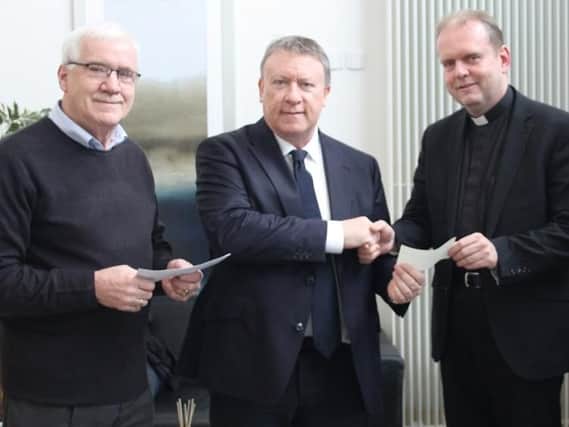 Derry City chairman Philip O'Doherty donates his Derry City monthly draw winnings to Fr Joe Gormley from St Marys Chapel in Creggan. Also pictured George Caldwell, Derry City Monthly Draw volunteer.