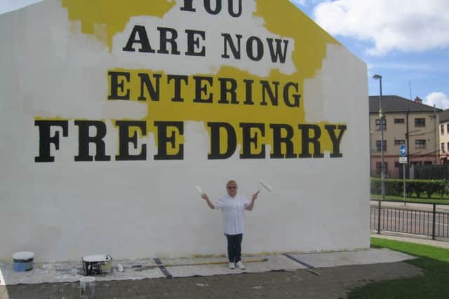 Arlene pictured painting Free Derry Wall.