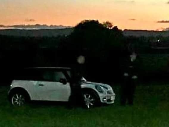 Police officers surround the vehicle after it is driven into a field in Co. Derry. (Photo: PSNI)