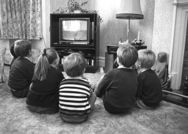 A group of young children huddled round the TV back in 1988. (Photo by Express/Getty Images)