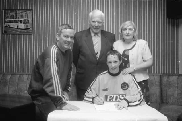 Barry Molloy signs his contract with Derby County in 1999 as Trojans boss, Raymond Carton and his parents Philomena and Joe look on proudly.