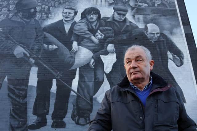 Mickey McKinney, whose brother William was killed on Bloody Sunday, stands beside a mural in the Bogside.