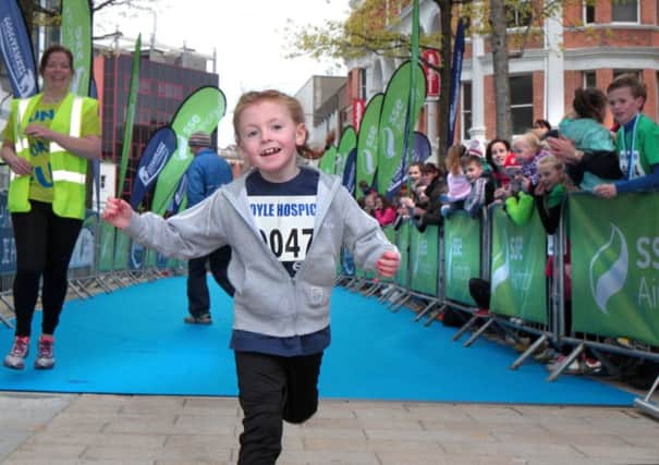 Little Cara O'Connor is cheered home in Guildhall Square after taking part in the childrens mini race during the Walled City Marathon last year. (Picture Margaret McLaughlin)