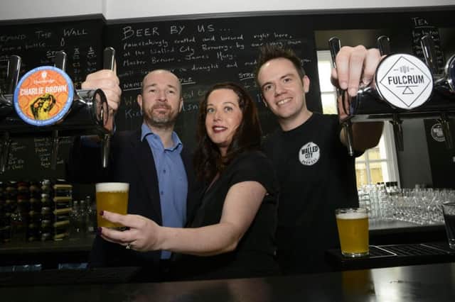 Louise and James Huey, proprietors of the Walled City Brewery, get a helping hand behind the bar from Caoimhin Corrigan, Director of the Ebrington Site, at their official opening on Friday. DER2415-102KM