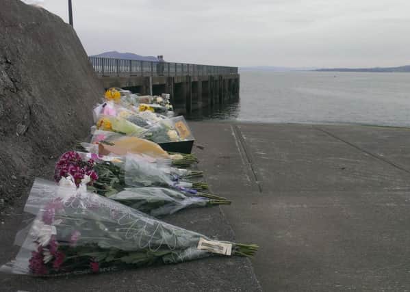 Some of the many floral tributes left at Buncrana pier in memory of the five people who died on Sunday.