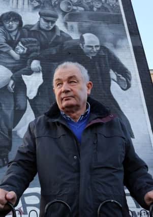 Mickey McKinney, whose brother William was killed on Bloody Sunday, stands beside a mural in the Bogside.