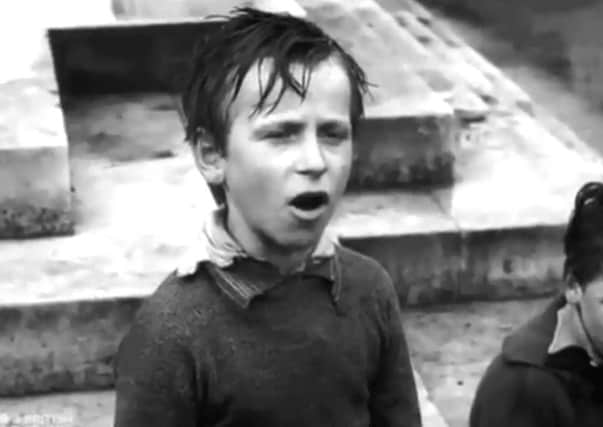 A screen shot of a young Derry boy singing for a penny for a Canadian soldier in the Diamond in Derry in 1945. The video belongs to the British Council Film Collection.
