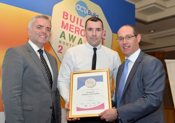 Raymond Harkin, manager of Murdock Builders Merchants, receiving the award from Minister Bell and Tadhg Donohoe, Octabuild chairman.
