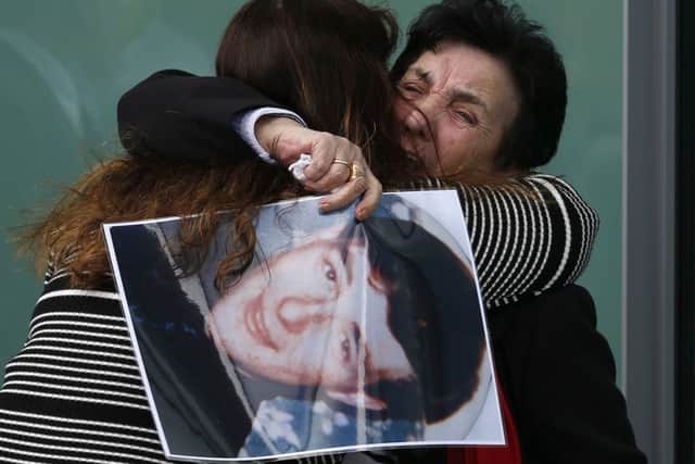 A relative holds a photo of Ian Thomas Glover, who died in the Hillsborough disaster, while they are hugged outside the Hillsborough Inquest in Warrington, where the inquest jury concluded that the 96 Liverpool fans who died in the Hillsborough disaster were unlawfully killed. (Owen Humphreys/PA Wire)