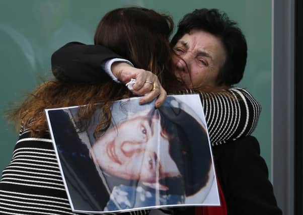 A relative holds a photo of Ian Thomas Glover, who died in the Hillsborough disaster, while they are hugged outside the Hillsborough Inquest in Warrington, where the inquest jury concluded that the 96 Liverpool fans who died in the Hillsborough disaster were unlawfully killed. (Owen Humphreys/PA Wire)