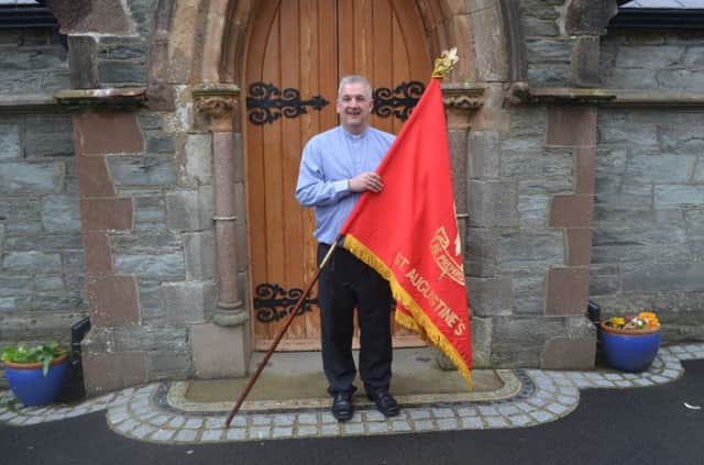 The Rector of St Augustine's Church, Rev Malcolm Ferry, holds the flag of First Londonderry Scout Troop, which was based at 'the Wee Church on the Walls' until 1972.