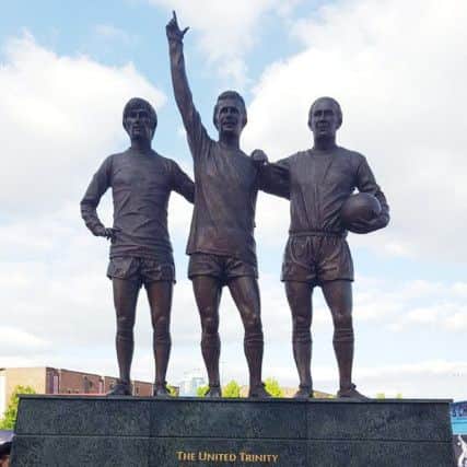 Eight year-old Kian Dawson pictured beside the famous statue dedicated to former Manchester United trio, George Best, Denis Law and Bobby Charlton.