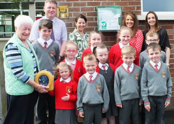 Mary Donaghy handing over the defibrillator to her granddaughter, Hope and other children from St Canice P.S, Bernie Carberry, Marcella Donaghy. Nicola O, Kane (classroom assistant) and St. Canice's P.S. Dungiven Principal Ciaran Loane.