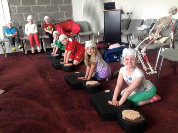 Children performing CPR on Flat Stan manikins at a previous first aid workshop