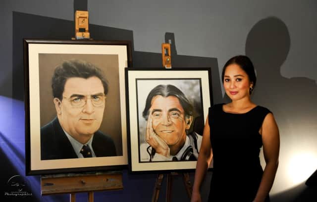 Artist Lolita Cooke with the portraits of John Hume and Gerry Anderson.