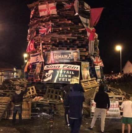 Youths mount the bonfire in the Bogside shortly after 11pm in order to set fire to it.
