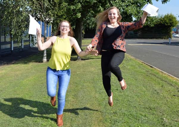 Two young women jump with joy on receiving their A-level results in 2015.
