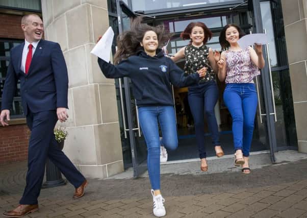 JUMPING FOR JOY!. . . .A bewildered looking St. Marys' College Vice Principal, Mr. Stephen Keown looks on as A Level students Kennedy Keeney-Robinson and twins Hannah and Rebecca Brown jump with joy after getting their grades yesterday morning. (Photo: Jim McCafferty Photography)