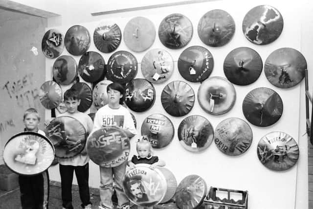 Local kids with some of the illustrated binlids which were produced at a workshop hosted by the Derry-based 20/20 Vision group. The binlids were carried at a march in Belfast to commemorate the 20th anniversary of internment and the 10th anniversary of the Long Kesh hunger strikes.