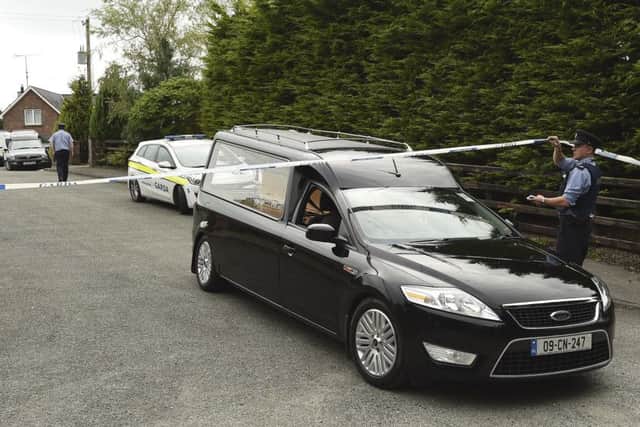 A Garda technical officer lifts tape as a hearse leaves the scene at Oakdene, Barconey, Ballyjamesduff in Cavan, where a family of five were found dead in their countryside home. Photo: Philip Fitzpatrick/PA Wire