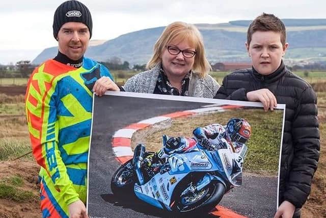 Louise McLean and Ben Mullan with Alistair Seeley, motorcycle road racer, handing over the signed poster to Ben who saved his little brother Rhys' life. Photo: Stephen McLean