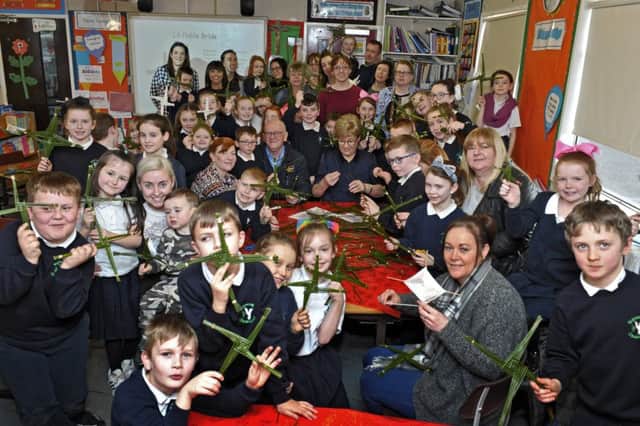 Bunscoil Cholmcille Steelstown Road pupils get a helping hand from parents and grandparents to make St Brigids crosses on the Saints recent feast day.  DER0517GS064