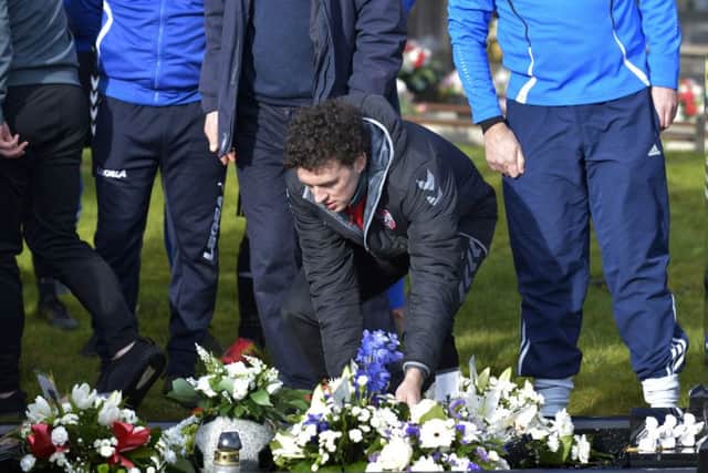 Derry City player Barry McNamee leaves a floral tribute on the grave of Mark Farren, in Ballybrack cemetery  Greencastle, on Saturday afternoon last. DER0517GS083