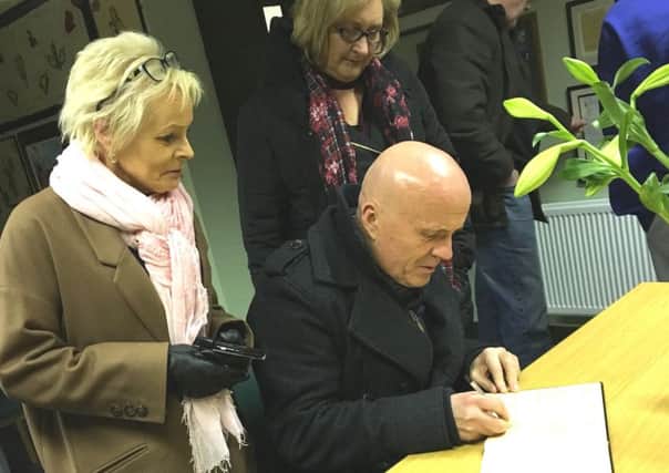 Sinn Colr. Sean McGlinchey signs a Book of Condolence in the Sinn Fein office in Dungiven. Looking on are Sinn Fein's Caroline White and Sinn Fein Colr. Brenda Chivers. Photo: Dylan Quigg.