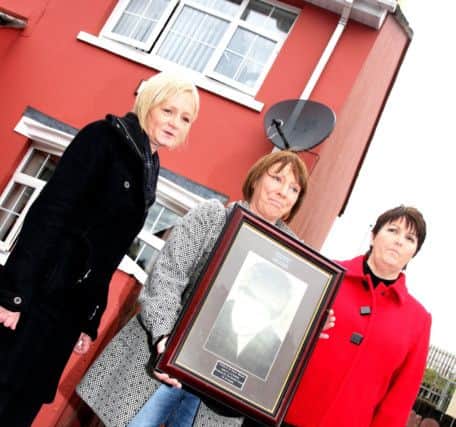 Daniel Hegarty's three sisters hold a framed photo of the 15 year-old near the spot where he was killed. From left, Philomena Conaghan, Kathleen Hegarty and Margaret Brady.