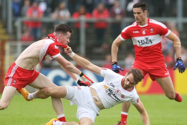 Tyrone's Ronan McNamee comes under pressure from Derry's Niall Loughlin.