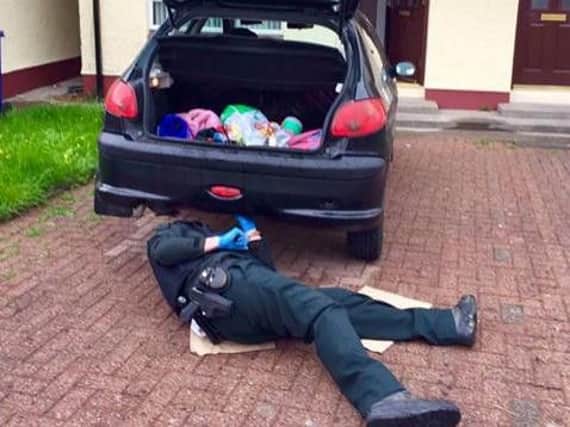 A PSNI officer helps to secure a wheel to the Galliagh woman's car.