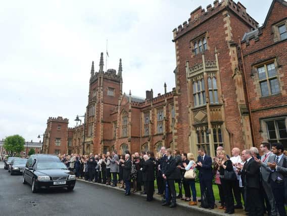 A round of applause for Professor Patrick Johnston as the Derry man's funeral cortege passes the Lanyon building at Queen's University, Belfast.