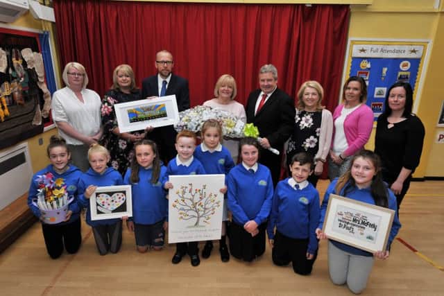 Mrs Catrina McFeely (centre), former principal, receives gifts from Gareth Blackery (left), principal St Pauls Primary School, and Ollie Green, Board of Governnors, at her retirement  appreciation event recently held in the school. Mrs McFeely retired after 37 years of teaching service. Included in the photograph are pupils and representatives of parents and the Board of Governors. DER2617GS027