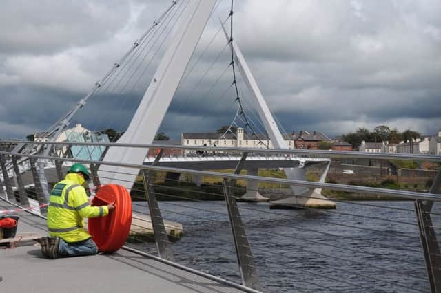 A workman places the housing for a lifebelt on the railings of the Peace Bridge in Derry back in 2011. Picture Martin McKeown. Inpresspics.com. 22.6.11