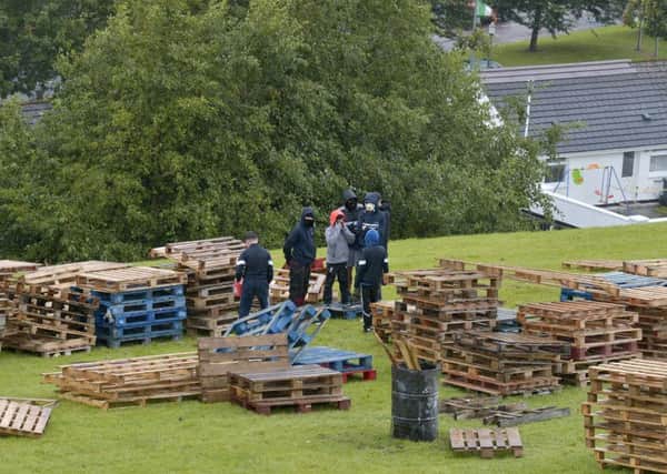Children, with their faces hidden, pictured yesterday constructing the controversial Bogside bonfire on the sloped green beneath Derry Walls. DER3317GS030