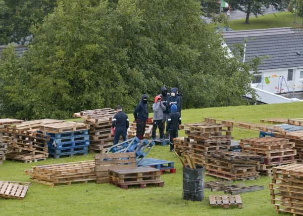 Children, with their faces hidden, pictured yesterday constructing the controversial Bogside bonfire on the sloped green beneath Derry Walls. DER3317GS030