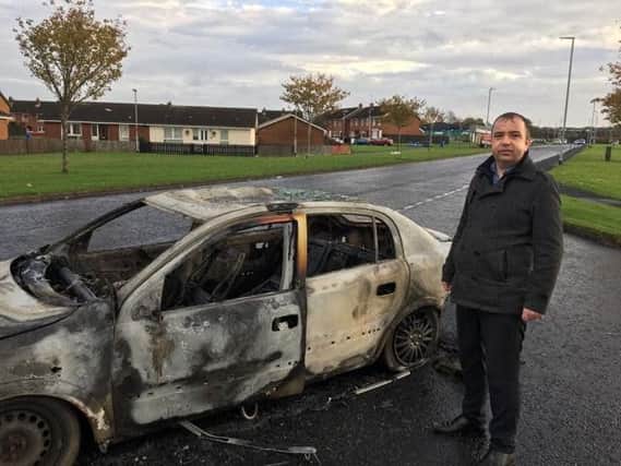 SDLP councillor Brian Tierney pictured beside the destroyed car.