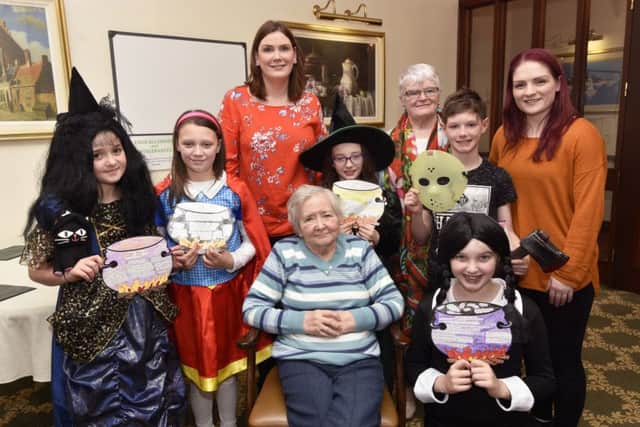 Brooklands Edenballymore Lodge resident Ita Gill, seated, pictured with some of the P6 pupils from Rosemount Primary School who read their Halloween stories during a visit to the home as part of a Verbal Arts Centre Reading Rooms intergenerational event. Included are, from left, Ashling McMenamin, teacher, Rosemary Quinn, volunteer, and Claire Harkin, Verbal Arts Centre. DER4317-124KM